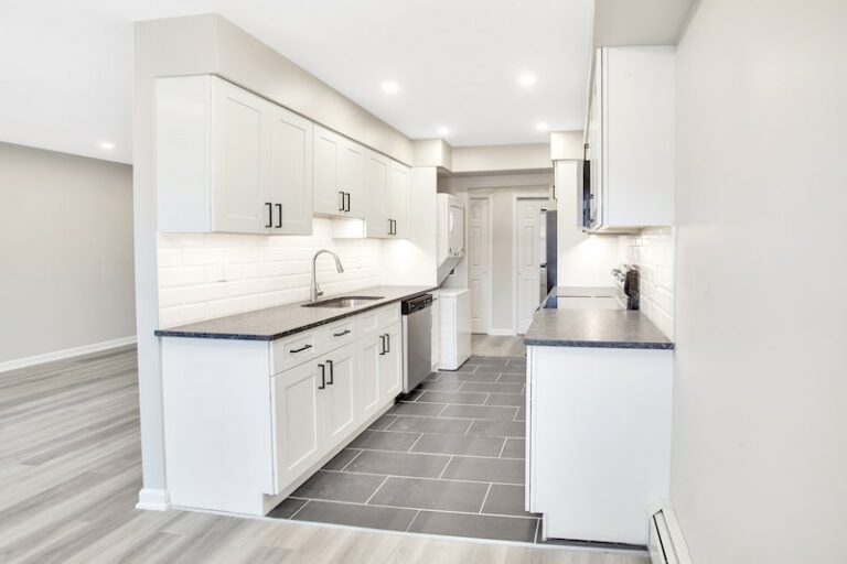 Galley style kitchen with tile flooring and white cabinetry